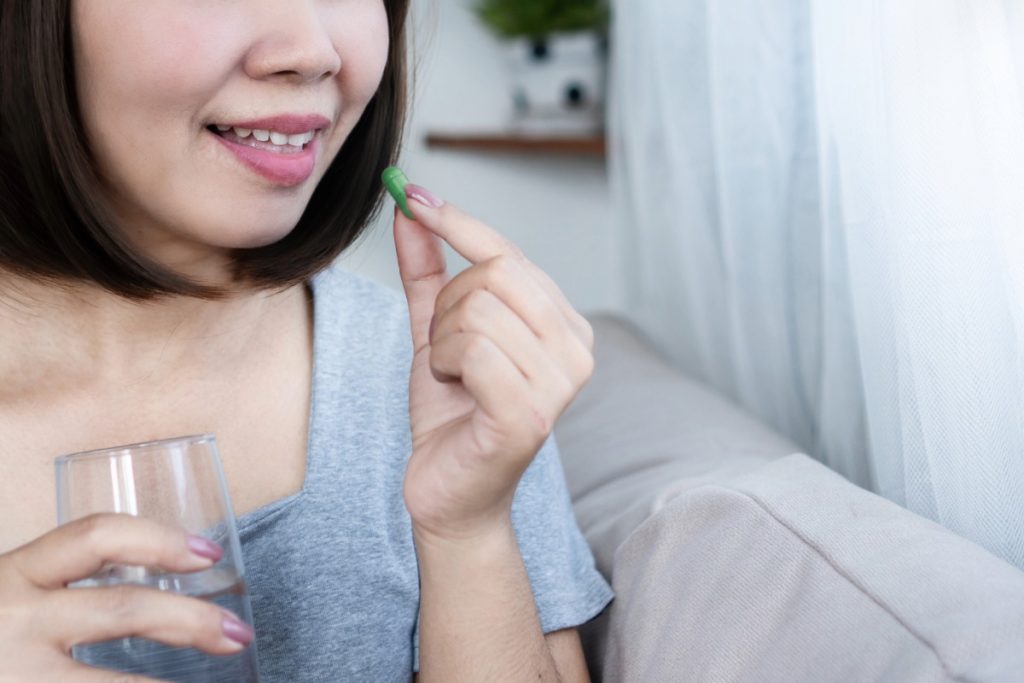 A lady taking kanna capsule with water