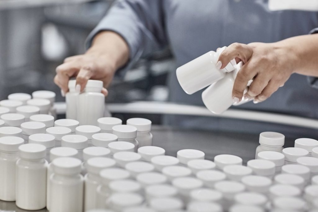 A person holding a small bottle of manufactured Kanna capsules in it