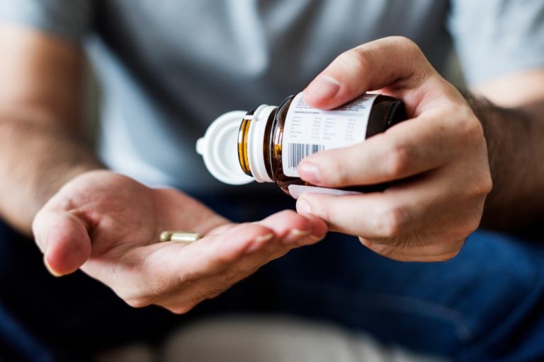 A person taking kanna capsules for therapeutic benefit.
