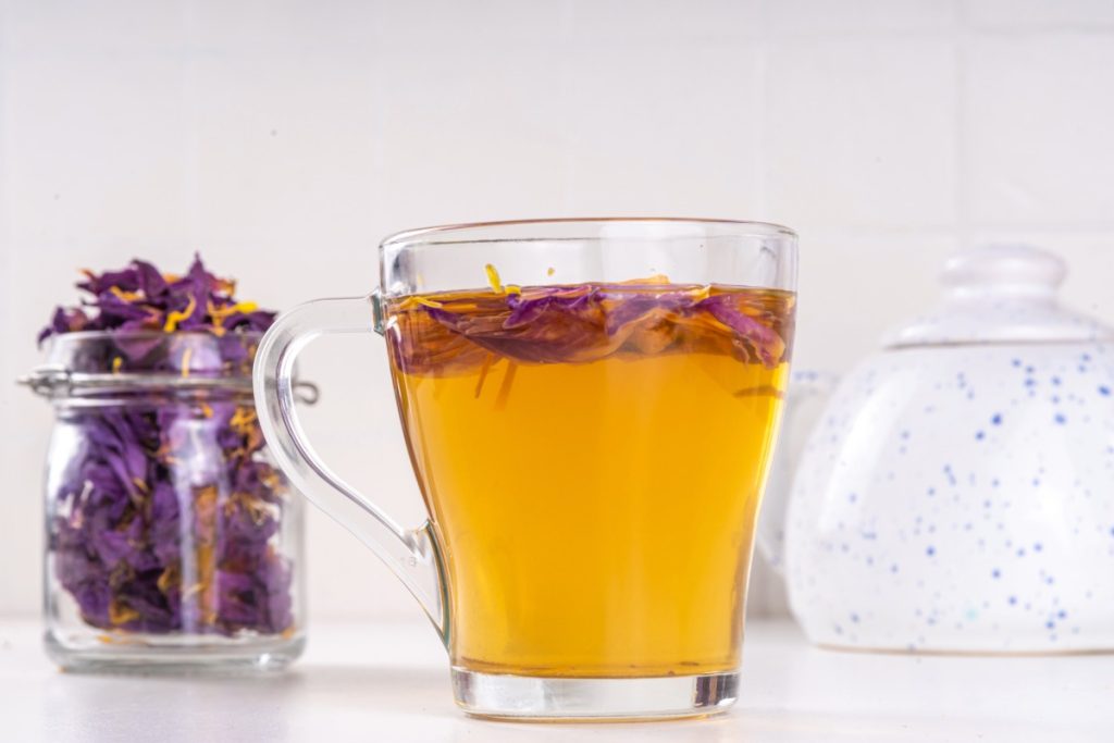Dried blue lotus petals in a jar with a cup of tea.