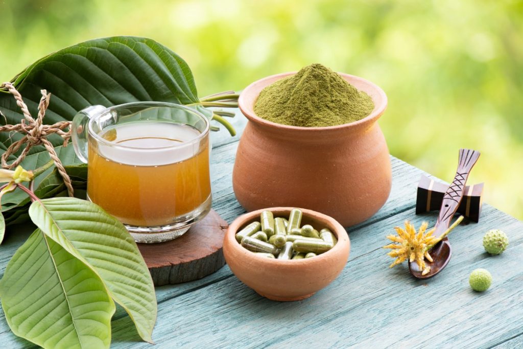 Kratom products displayed alongside fresh kratom leaves